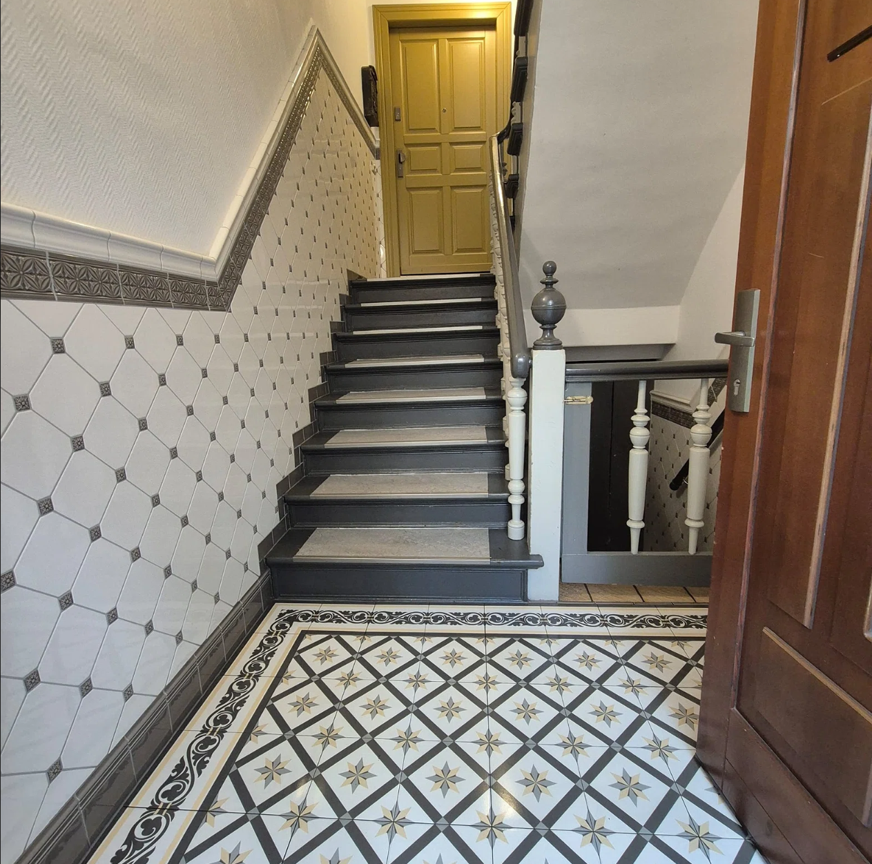 Heller Hausflur mit Schachbrettboden und Treppenaufgang